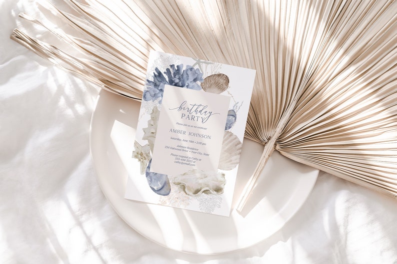 May include: A light blue and white birthday party invitation with a watercolor design of seashells and coral. The text on the invitation reads "birthday party" and "Amber Johnson".