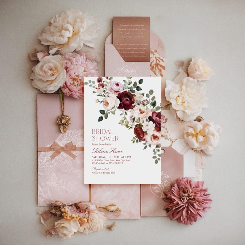 May include: A rectangular bridal shower invitation card featuring a floral arrangement of burgundy, blush, and cream flowers with green leaves. The text reads: BRIDAL SHOWER, join us in celebrating, Rebecca Howe, SATURDAY, JUNE 27TH AT 2 PM.