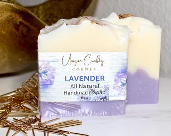 May include: Two bars of handmade lavender soap. The soap has a layered design with a purple base and a creamy white top. The label reads "Unique Crafty Corner" and "Lavender All Natural Handmade Soap". The soap is 4 oz.