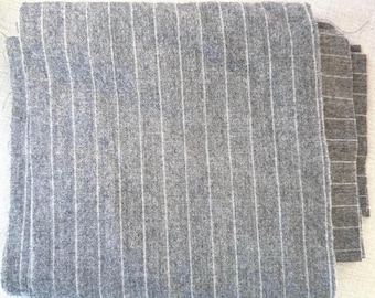 May include: Gray and white striped fabric with a subtle texture. The fabric is folded in half and the edges are visible.