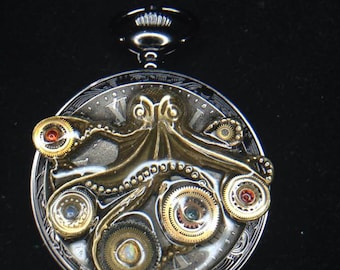 May include: A silver and gold steampunk-style pocket watch with an octopus design. The octopus is made of resin and has a detailed texture. The watch face has Roman numerals and is surrounded by gears. The watch has a black crown and a silver chain.