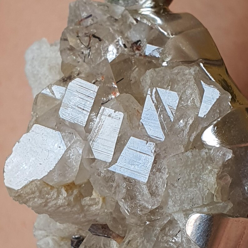 Puede incluir: Primer plano de un grupo de cristales de cuarzo transparente con superficies reflectantes. Los cristales est&aacute;n dispuestos en una formaci&oacute;n natural, con algunas &aacute;reas opacas y otras transparentes. El cuarzo se encuentra sobre un fondo neutro.