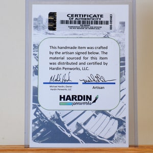 May include: A certificate of authenticity for a handmade item. The certificate is in a clear plastic holder and features the Hardin Penworks, LLC logo, signatures, and text. The background has a blue and white design.