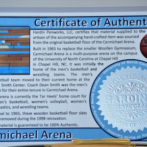 Peut inclure: Certificat d'authenticit&eacute; pour les souvenirs de Carmichael Arena. Le document comprend du texte et un logo de basket-ball Wilson NCAA. Le certificat indique que le mat&eacute;riau provient du parquet d'origine.