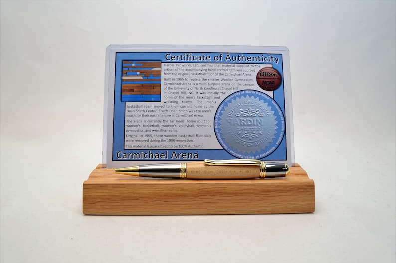 Peut inclure: Stylo artisanal fabriqu&eacute; &agrave; partir du parquet original du Carmichael Arena, avec un certificat d'authenticit&eacute;. Le stylo a un corps en bois clair, des accents argent&eacute;s et des garnitures dor&eacute;es. Le stylo est expos&eacute; sur un pr&eacute;sentoir en bois.