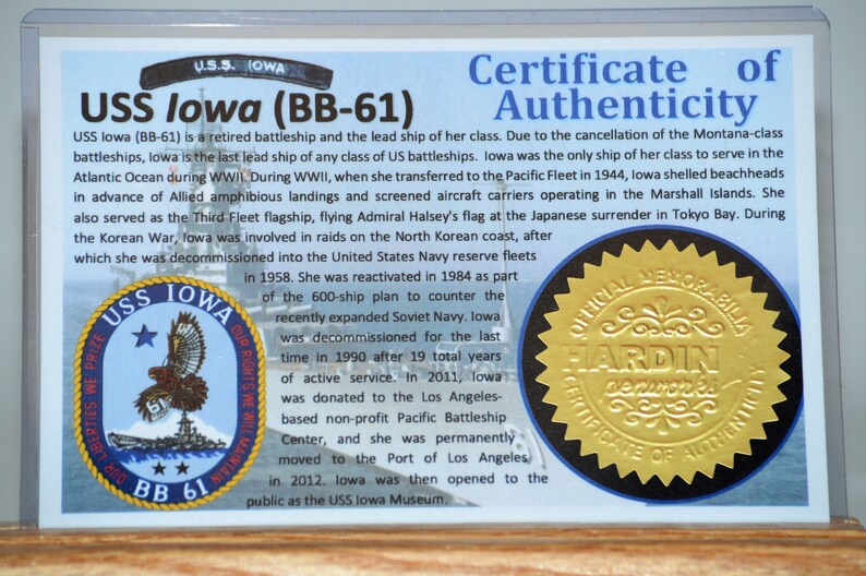 Puede incluir: Certificado de autenticidad para el USS Iowa (BB-61), un acorazado retirado. El certificado presenta texto sobre la historia del barco, un emblema del barco y un sello dorado con el texto "OFFICIAL MEMORABILIA".