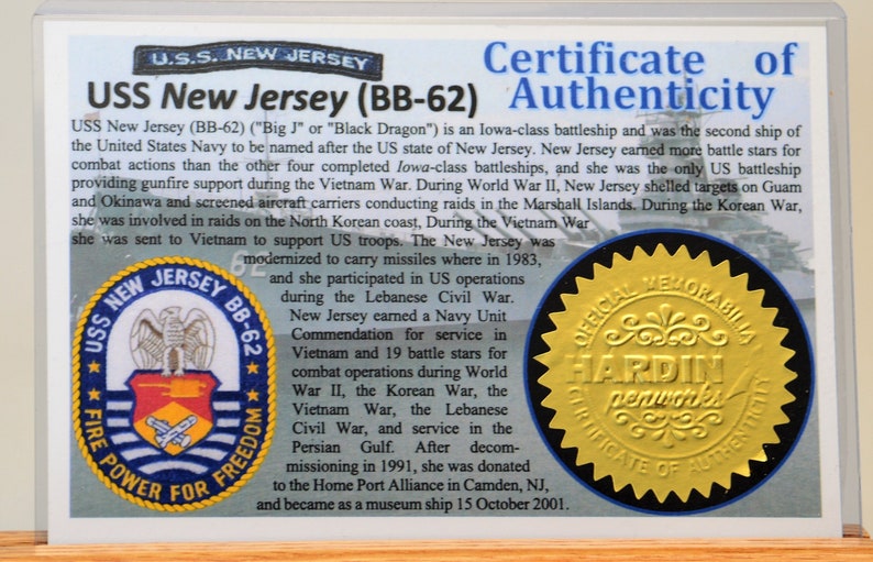 May include: A certificate of authenticity for the USS New Jersey (BB-62). The certificate includes text about the ship's history, including its service in World War II, the Korean War, and the Vietnam War. The certificate has a gold seal.