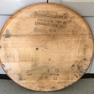 May include: Circular wooden barrel lid with visible wood grain and dark markings. The text "LEM MOTLOW PROP. INC LYNCHBURG, TENN" is printed on the surface, along with "RC 53" and other markings. The lid is approximately 36 inches in diameter.