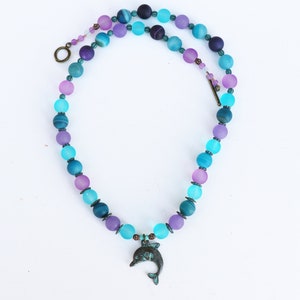 Collier dauphin violet et turquoise.  Pendentif dauphin bondissant en métal.   Boucles d’oreilles répertoriées séparément.
