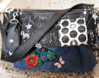 Black and colorful spacious shoulder bag in a mix of patterns and materials, leather and fabric, lots of details