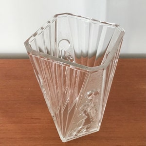 May include: A clear glass vase with a geometric design and a textured surface. The vase has a wide mouth and a narrow base.