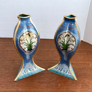May include: A pair of blue and gold cloisonn&eacute; vases shaped like fish with floral designs. The vases are approximately 10 inches tall.