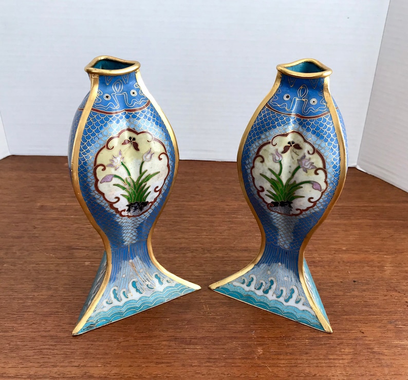 May include: A pair of blue and gold cloisonn&eacute; vases shaped like fish with floral designs. The vases are approximately 10 inches tall.