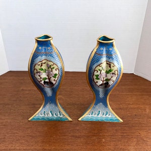 May include: A pair of blue and gold cloisonn&eacute; vases shaped like fish with floral designs. The vases are about 10 inches tall.