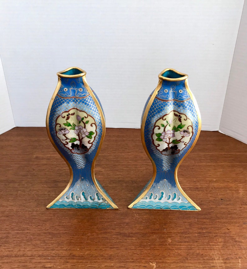 May include: A pair of blue and gold cloisonn&eacute; vases shaped like fish with floral designs. The vases are about 10 inches tall.