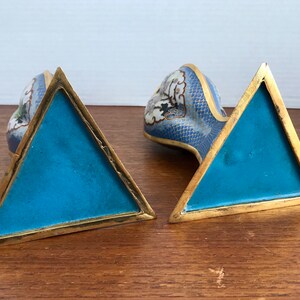 May include: A pair of blue and white cloisonn&eacute; bookends in the shape of a dragon. The bookends have a triangular base with a gold trim.