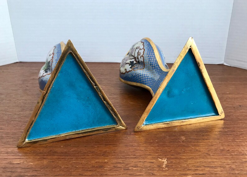 May include: A pair of blue and white cloisonn&eacute; bookends in the shape of a dragon. The bookends have a triangular base with a gold trim.