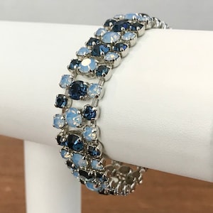 Peut inclure: Un bracelet argenté avec un design dégradé ombré de cristaux bleus et blancs. Le bracelet est fait d'une chaîne avec de petits cristaux ronds.