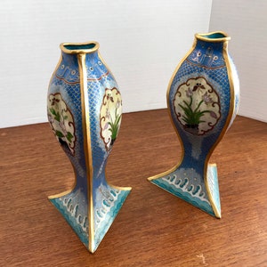 May include: A pair of blue and gold cloisonn&eacute; vases with floral designs. The vases are shaped like fish and have a triangular base.