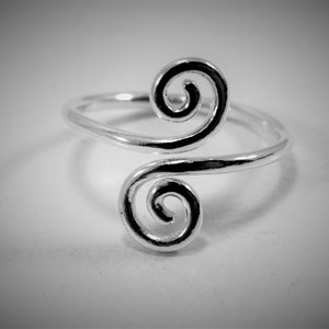 May include: A silver ring with a double spiral design.
