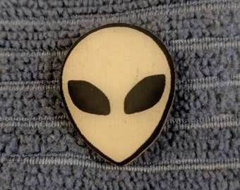 Puede incluir: Una cara de extraterrestre blanca con ojos negros, sobre un fondo azul texturizado.