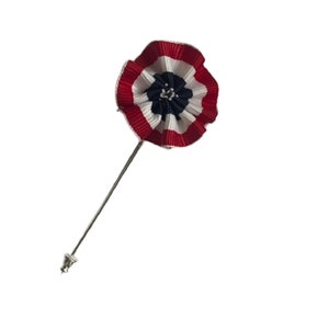 May include: A patriotic lapel pin featuring a pleated rosette design in red, white, and blue. The pin has a silver-colored stem and a decorative end. This accessory is suitable for patriotic events.