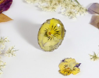 Bague avec une fleur véritable : pensée jaune du jardin, gros cabochon ovale, monture inox réglable