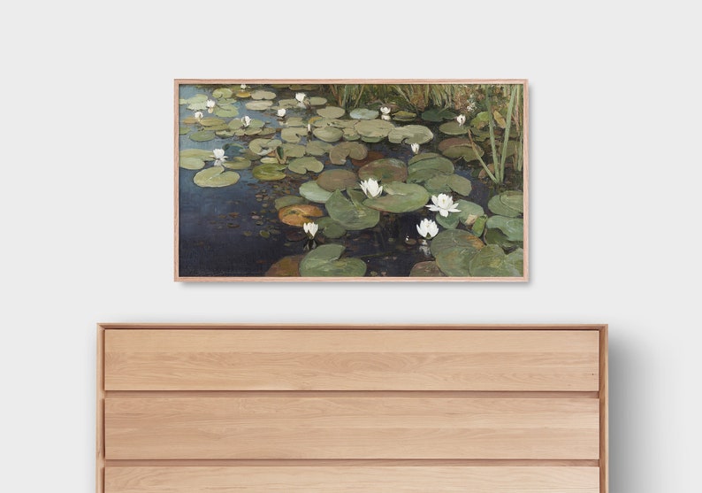 May include: A framed painting of a pond with white water lilies and green lily pads. The water is a dark blue color and the background is a light green.