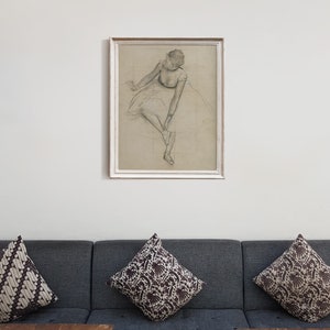May include: A framed black and white drawing of a ballerina in a white tutu, sitting and tying her shoe.
