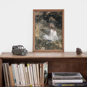 May include: A framed painting of a young girl sitting in a field of flowers. The painting is in a wooden frame and is hanging on a wall above a shelf with books and a toy car.