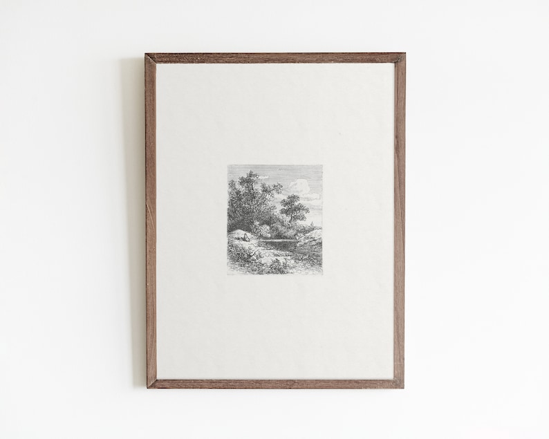 May include: A black and white framed print of a landscape scene with trees and a body of water. The print is in a simple wooden frame.