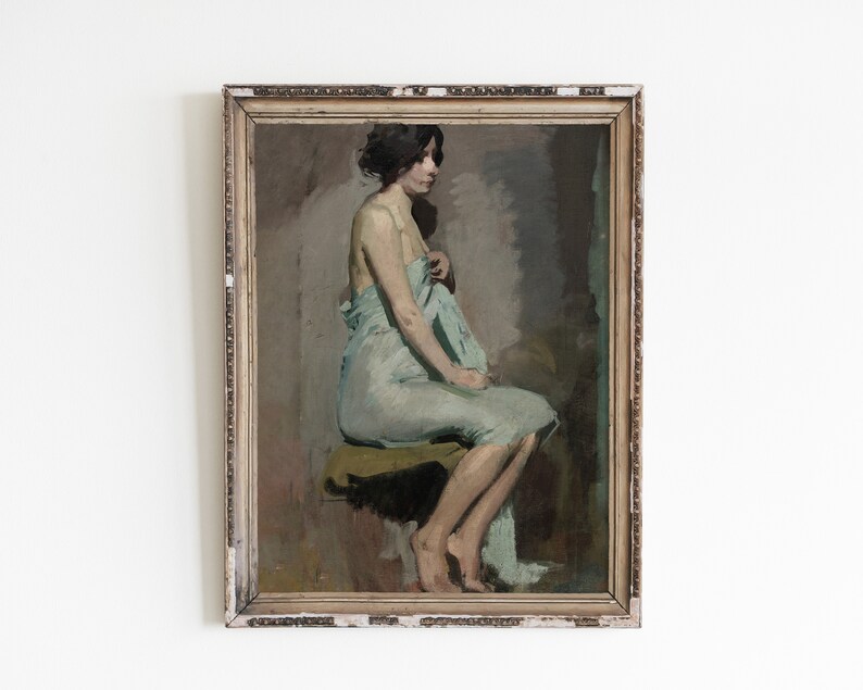 May include: A framed oil painting of a woman sitting on a stool, wearing a light blue draped garment. The woman is facing away from the viewer, and her hair is pulled back. The painting is set against a neutral background.