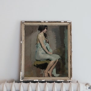 May include: A framed painting of a woman in a light blue draped garment, sitting on a stool. The painting is in a gold frame with a distressed finish.