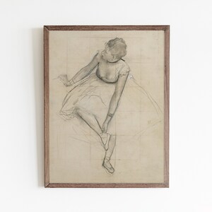 May include: A framed black and white pencil drawing of a ballerina in a tutu, adjusting her shoe. The drawing is on a light brown paper with a grid pattern.