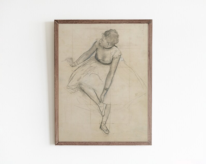 May include: A framed black and white pencil drawing of a ballerina in a tutu, adjusting her shoe. The drawing is on a light brown paper with a grid pattern.