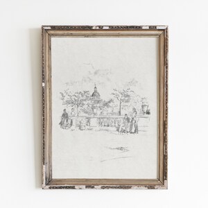 May include: A framed black and white pencil drawing of a city scene with a church in the background and people walking in the foreground.