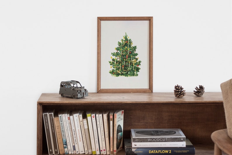 May include: A framed print of a vintage Christmas tree with ornaments and lights on a wooden shelf with books and a toy car.