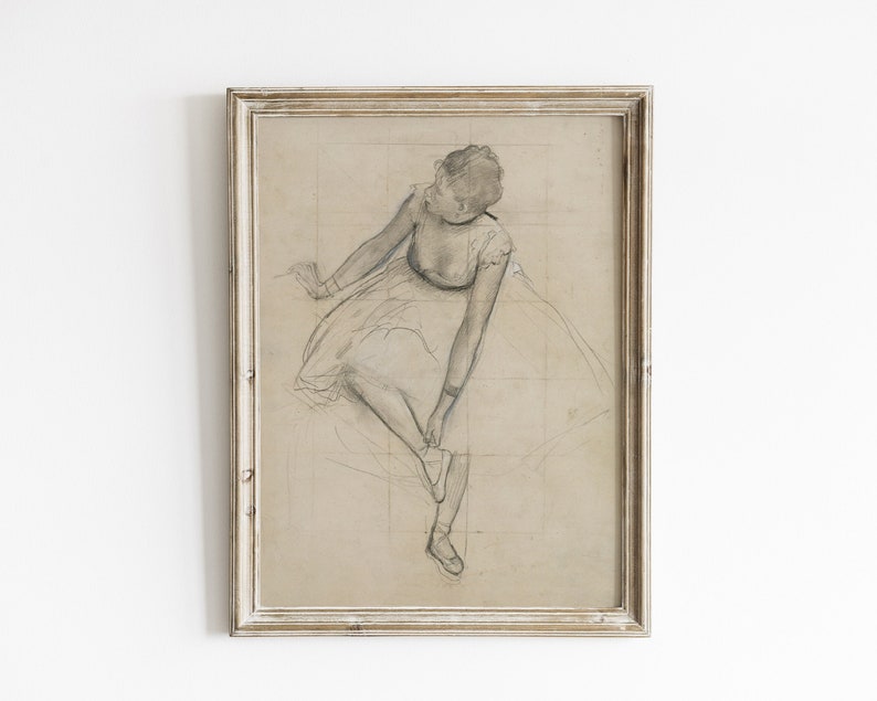May include: A framed black and white pencil drawing of a ballerina in a tutu, sitting and tying her shoe.