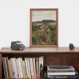May include: A wooden shelf with a framed painting of a field of wildflowers, a small toy car, and two pine cones. The shelf is filled with books, including "The Woodcut" and "Data Flow 2".