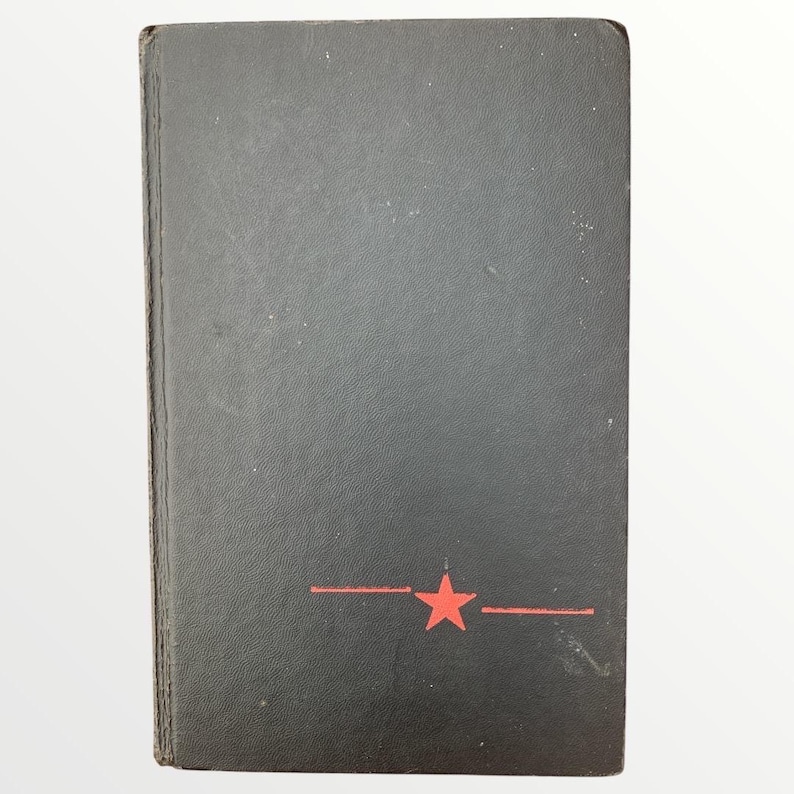 May include: A black book with a red star and two horizontal lines. The book has a worn appearance and a slightly textured surface. The cover is a solid black color.
