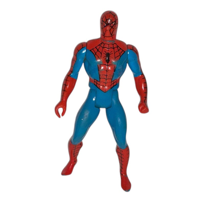 May include: A Spider-Man action figure in a standing pose. The figure is primarily blue and red, with a spiderweb pattern on the red areas. A black spider emblem is on the chest.