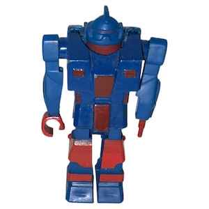 May include: A blue and red toy robot figure. The robot has a blue head, torso, arms, and legs with red accents on the chest, legs, and hands. The robot has a small fin on top of its head.