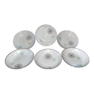 May include: A set of three ceramic mugs with a speckled, matte finish. Each mug features a different color: light blue, cream, and gray. The mugs have a simple, modern design and a comfortable handle.