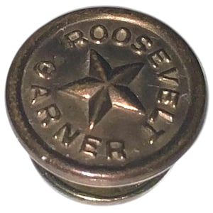 Könnte beinhalten: Ein kreisförmiger, bronzefarbener Knopf mit den Worten "ROOSEVELT GARNER" um einen zentralen Stern. Der Knopf hat ein erhabenes Design und einen metallischen Glanz. Text und Stern sind leicht erhaben.