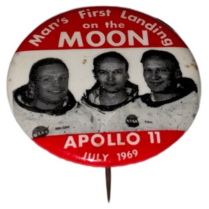 Könnte beinhalten: Ein roter und weißer Knopf mit einem Bild von drei Astronauten und dem Text "Man's First Landing on the MOON APOLLO 11 JULY 1969".
