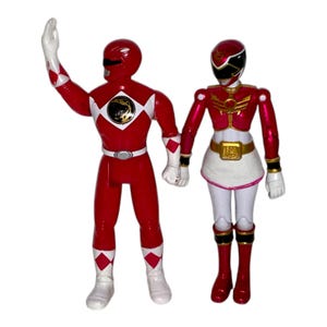 May include: Two Power Ranger action figures. The red Ranger is waving with white gloves and diamond accents. The female Ranger has a white skirt, gold belt, and red boots. Both figures are red and white.