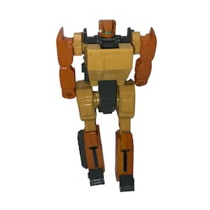 May include: A vintage toy robot in shades of tan, brown, and black. The robot has a boxy torso, articulated limbs, and a detailed head with green accents. The toy is standing upright against a white background.