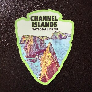 May include: A green and white sticker with a picture of a rocky island and blue water. The text "CHANNEL ISLANDS NATIONAL PARK" is printed in black.