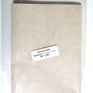 May include: Aida cloth in a neutral oatmeal color, packaged in clear plastic. The label reads "14 count Aida 'Oatmeal'" and lists the dimensions as 30" x 36" (76.2 cm x 91.4 cm). Ideal for cross-stitch and embroidery projects.