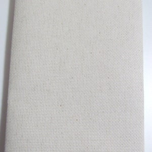 May include: A rectangular piece of off-white cross-stitch fabric, folded in half. The fabric has a visible grid pattern, ideal for embroidery or cross-stitch projects. The material appears to be a natural fiber, possibly cotton or linen.